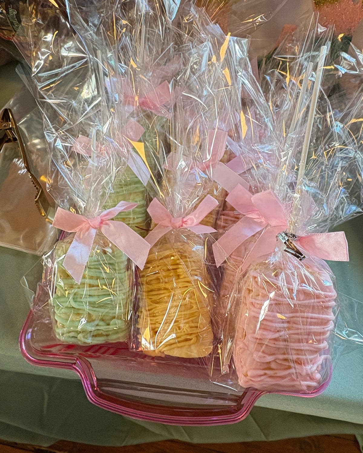 Rice crispy treats drizzled in green, yellow and pink chocolate, individually wrapped and tied with pink satin bows
